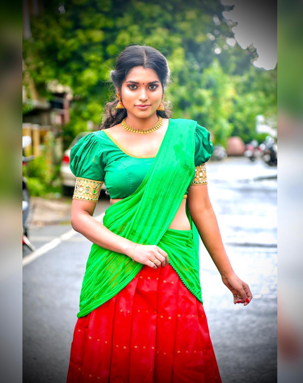 Chandhrika Revathi wearing a light gray saree with dark borders while standing outdoors and holding the drape with both hands.