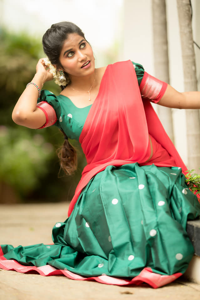 Aadhirai Soundararajan posing outdoors in a vibrant emerald green and coral traditional drape.