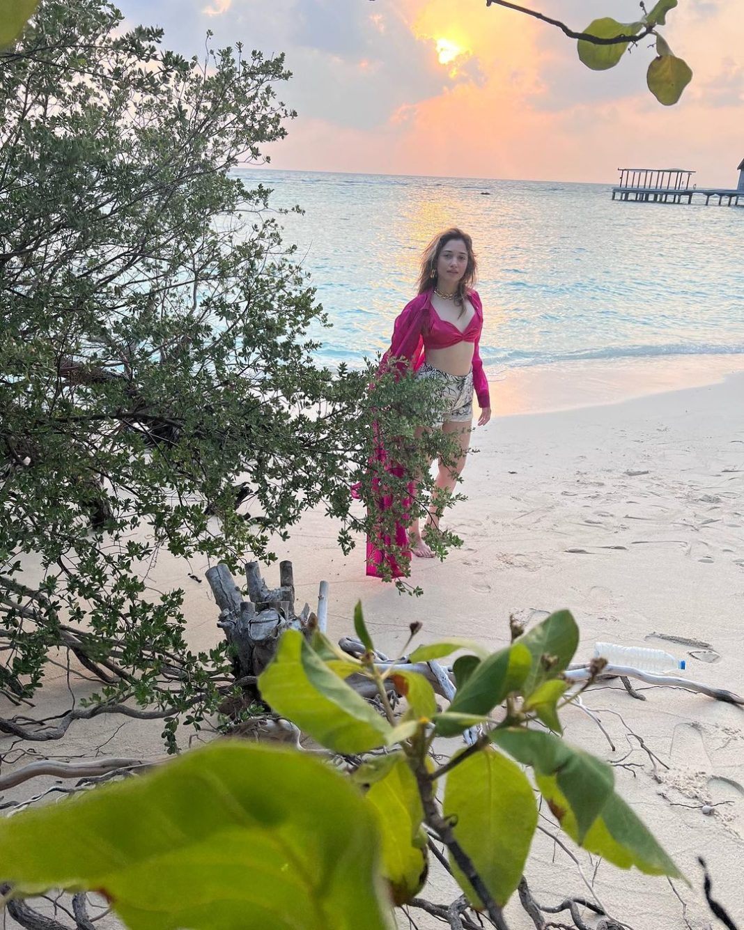 Tamannaah Bhatia poses in a vibrant outfit with elegant jewelry and striking makeup.