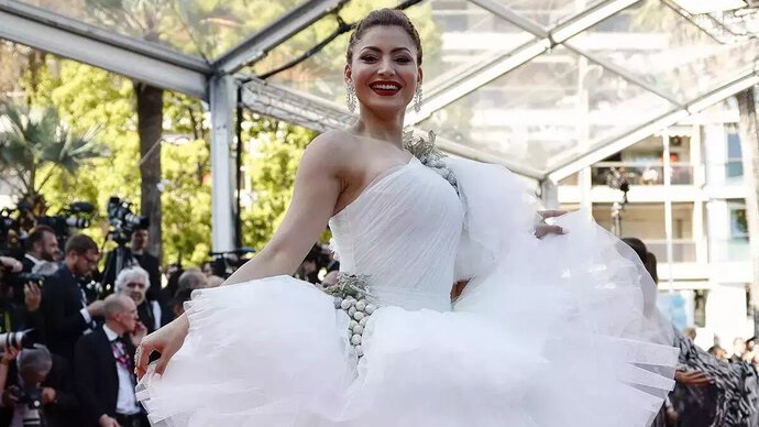 Urvashi Rautela is seen wearing a vibrant blue ensemble with intricate detailing and dramatic hair styling.