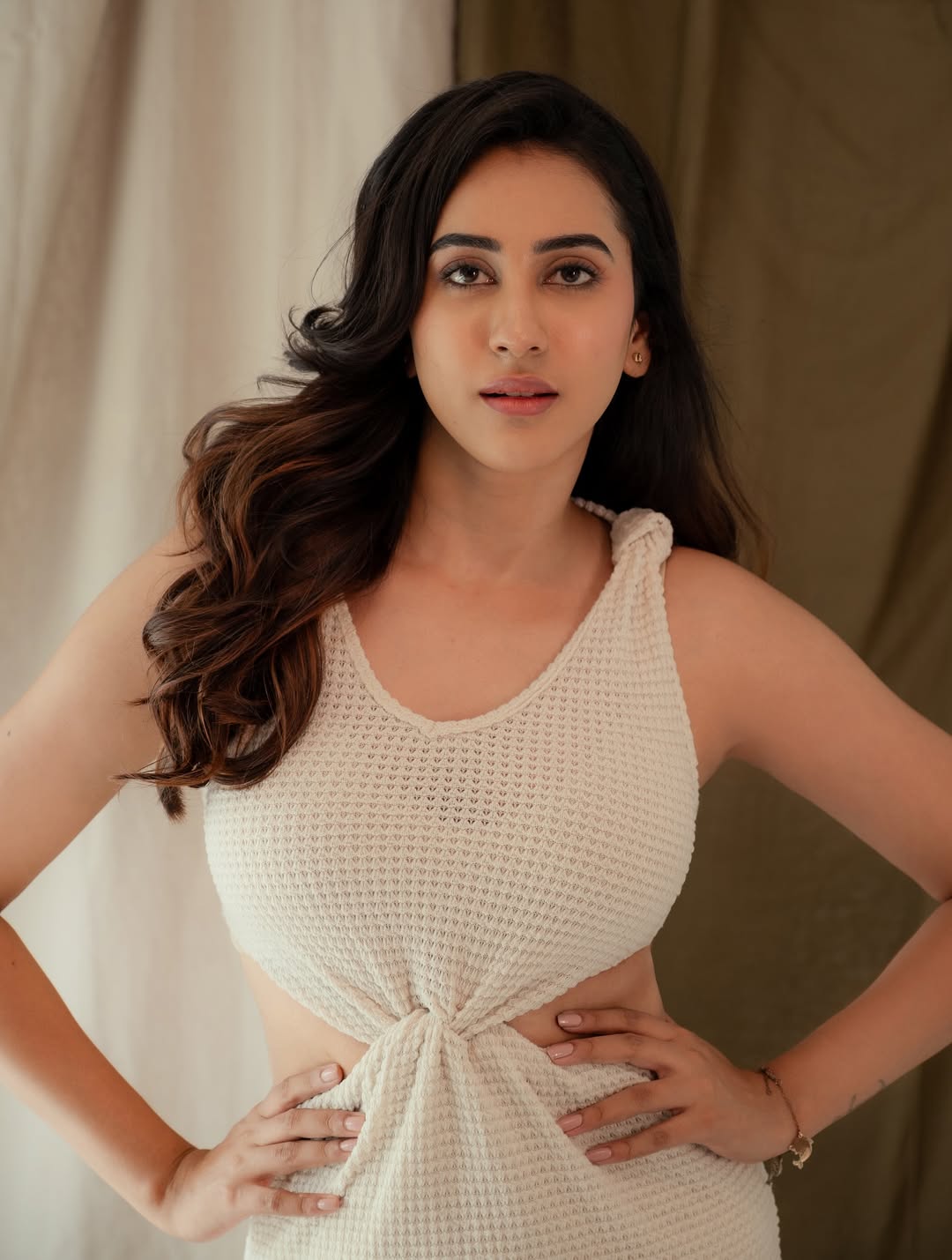Akshaya Hariharan poses in a stylish outfit with dramatic makeup and hair.
