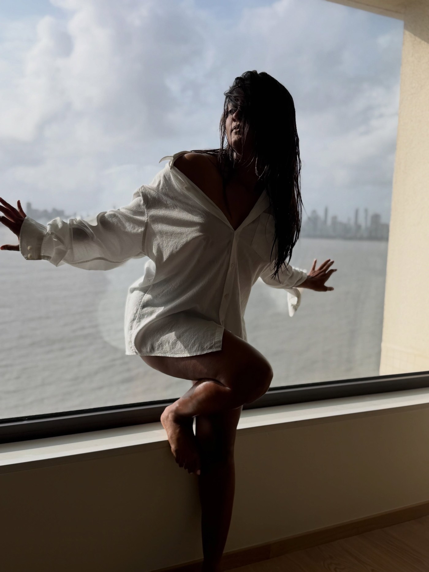Amika Shail is spotted embracing understated cool in a relaxed oversized white shirt against a city backdrop.