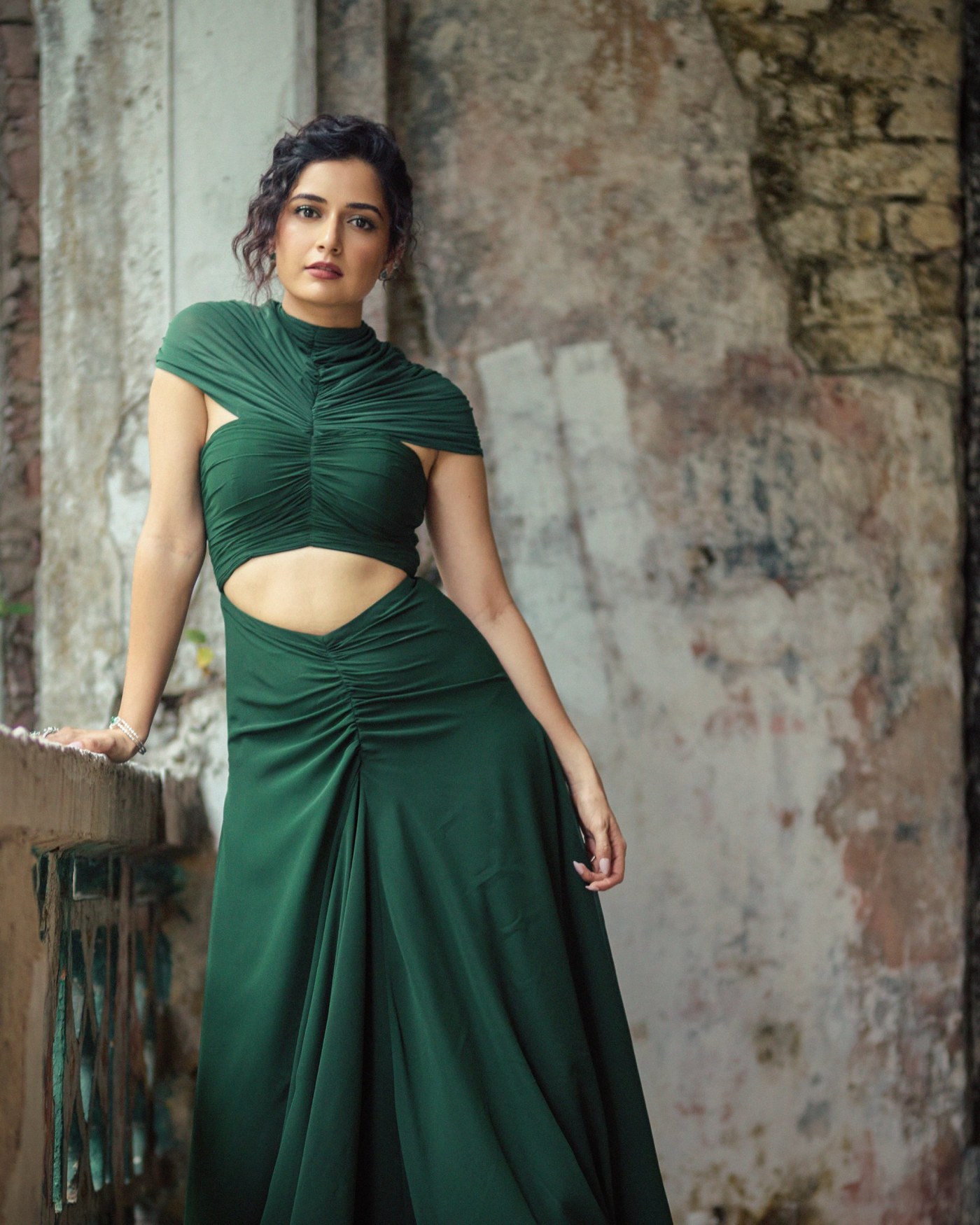 Ashika Ranganath stands in a deep emerald green gown, showcasing a modern, structured two-piece ensemble.
