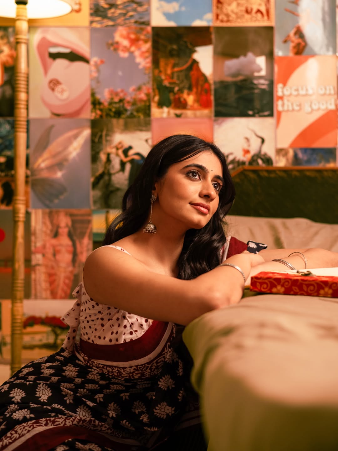 Cherukuri Maanasa Choudhary reclining with a joyful smile in soft light, surrounded by rich decor.