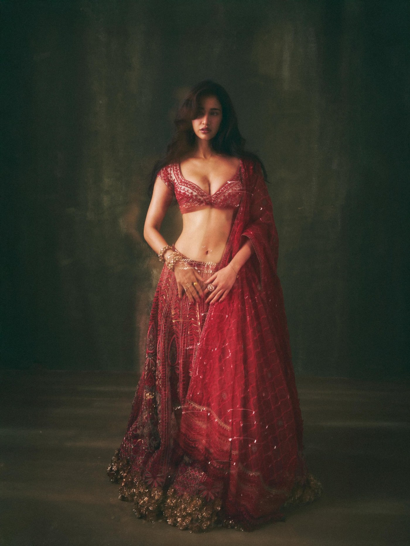 Disha Patani is styled in a rich red lehenga with ornate embroidery for a contemporary festive look.