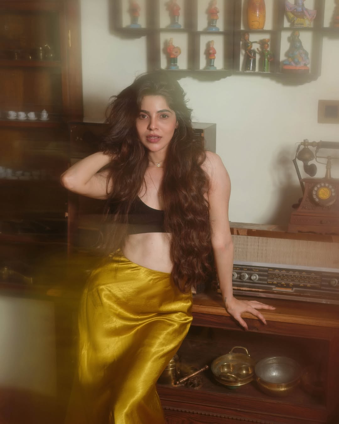 Divya Bharathi poses elegantly in a black crop top and mustard yellow satin wrap skirt.