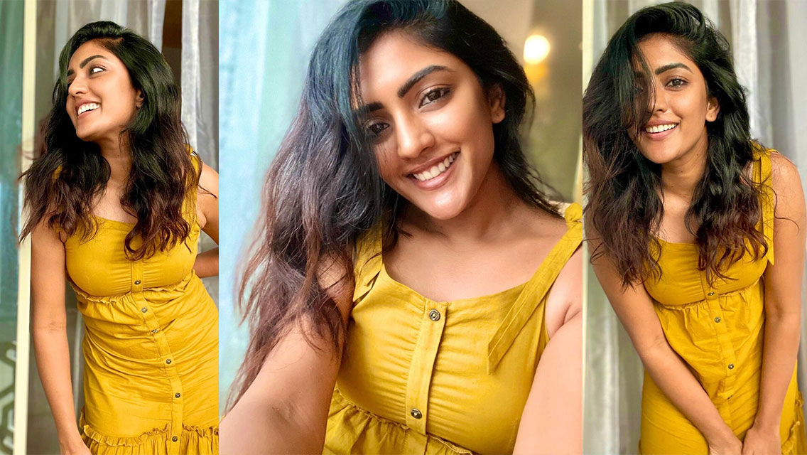 Eesha Rebba in a bright yellow, textured sleeveless garment, smiling warmly indoors near a window.