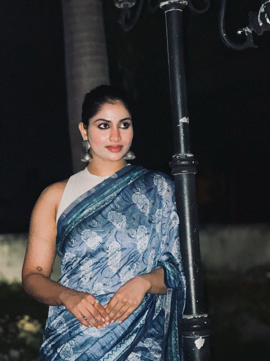 Shivani Narayanan is captured in a modern public setting wearing an intricate blue and white Indian garment.