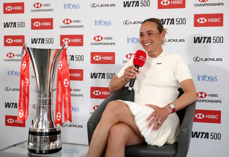 Emma Raducanu poses with a confident smile at an event, radiating poise and grace.
