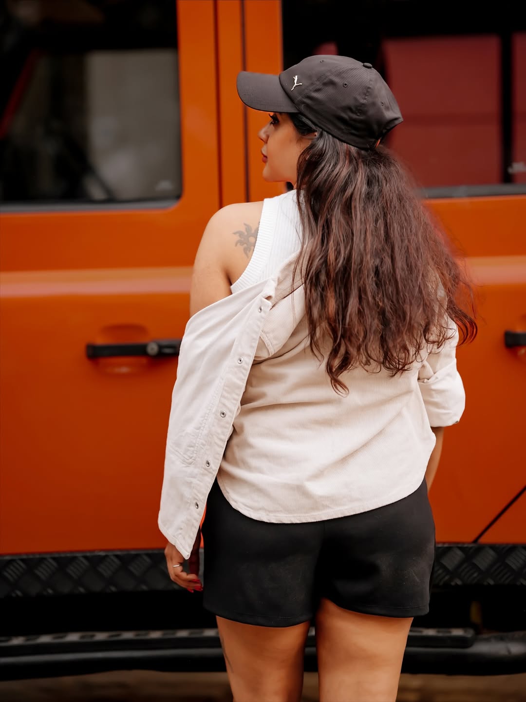 Gayathri Shan smiling outdoors in a white shirt and geometric patterned skirt, adorned with black bracelets.
