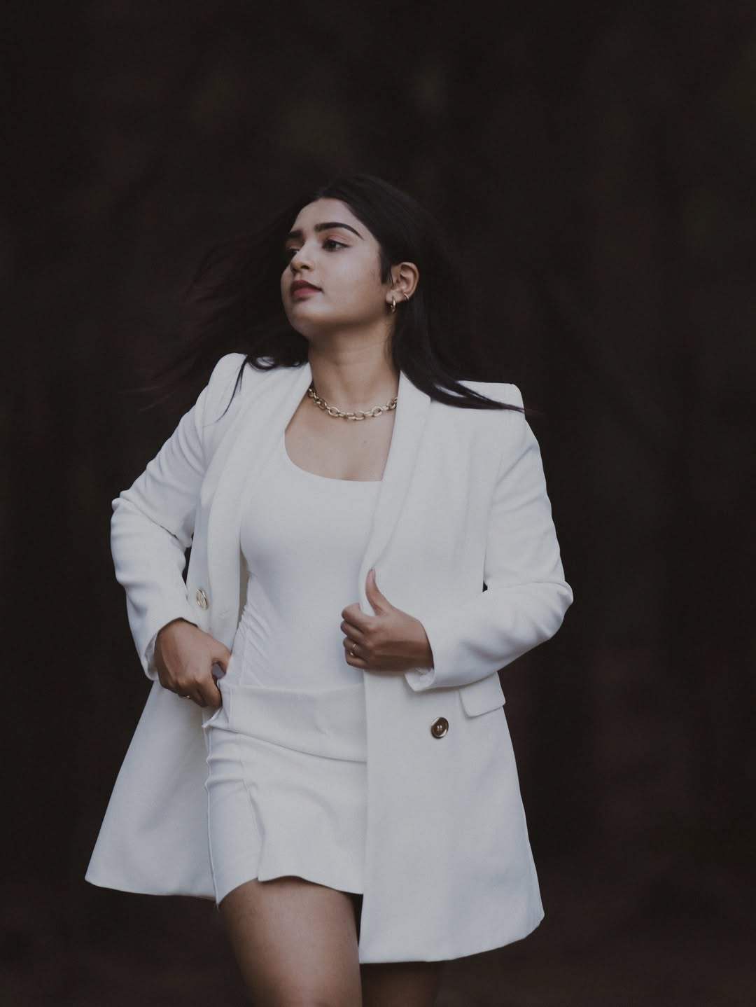 Gouri Kishan poses dramatically outdoors in a fitted white mini-dress, showcasing natural grace and style.
