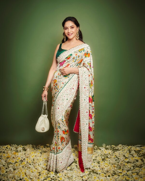 Madhuri Dixit is posing beautifully with a smiling, radiant expression and traditional attire.