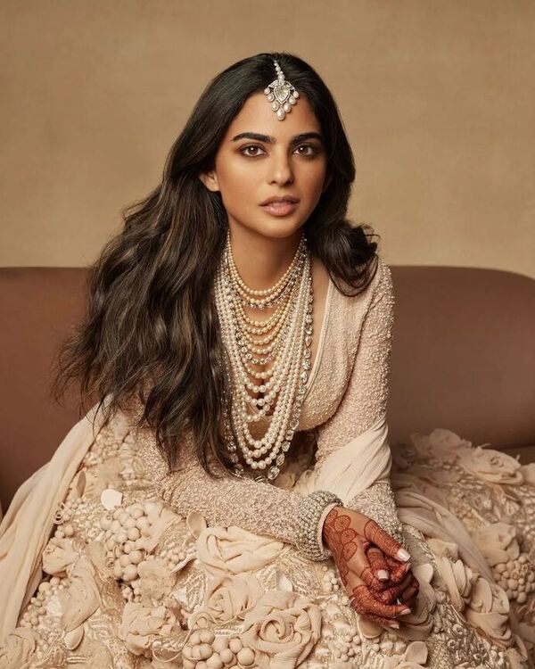 Isha Ambani is captured wearing a dazzling silver ensemble with intricate detailing in Photo 1.