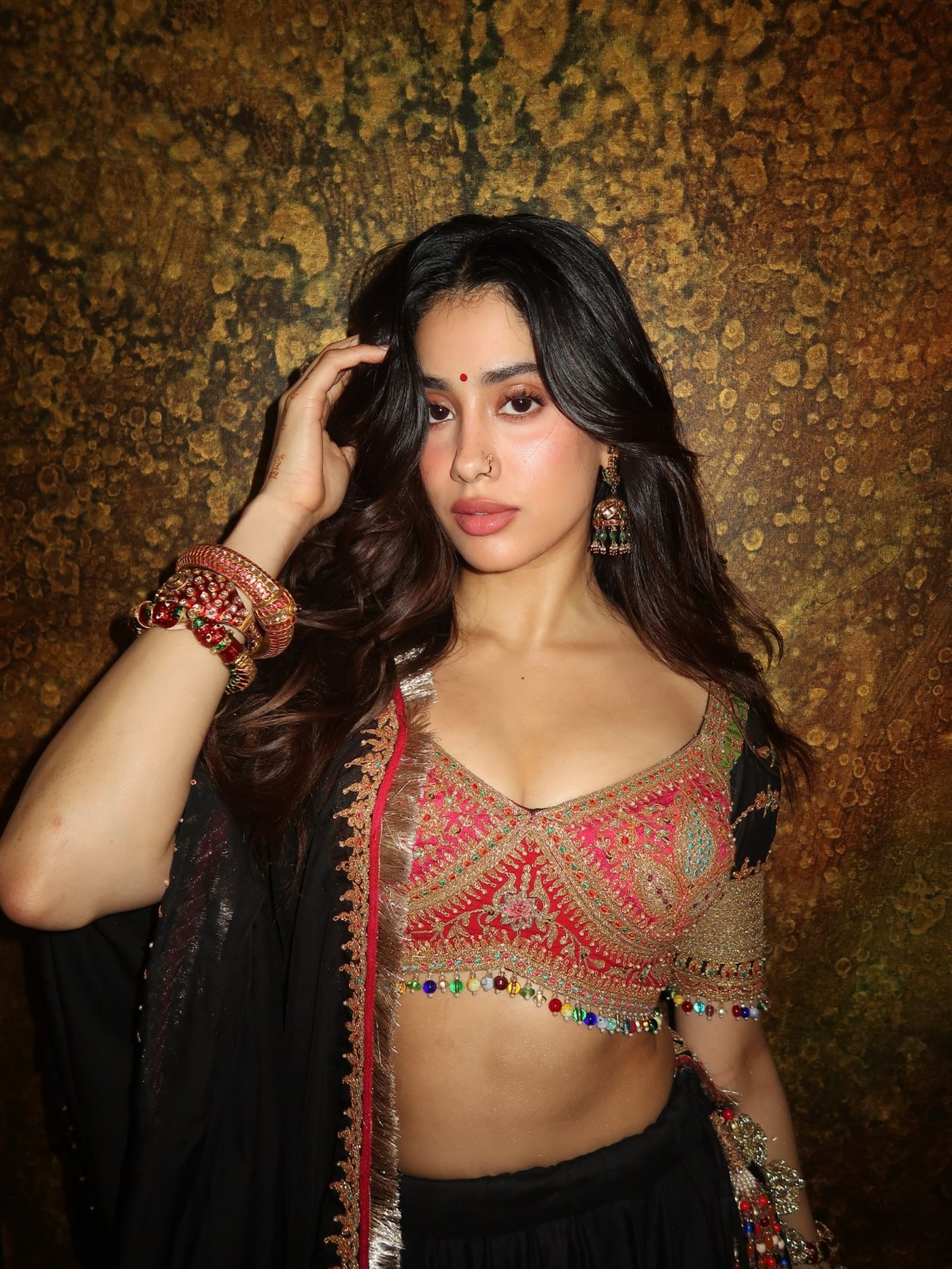 Janhvi Kapoor flaunts a luxurious black velvet lehenga adorned with intricate gold embroidery and royal jewelry.