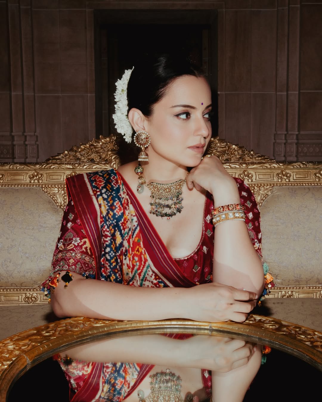 Kangana Ranaut posing confidently in a vibrant, heavily embellished outfit.