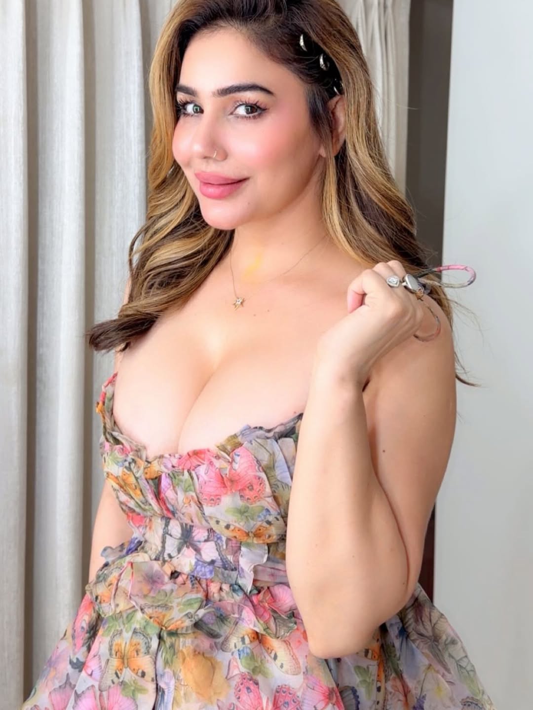 Kangna Sharma posing indoors wearing a strapless dress with a multi-colored floral print and wavy hair.