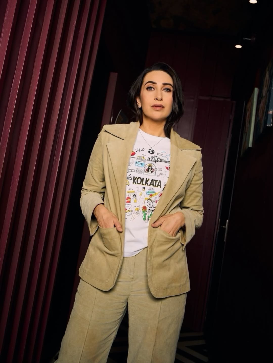 Karisma Kapoor poses gracefully in a vibrant outfit against an elaborate backdrop.