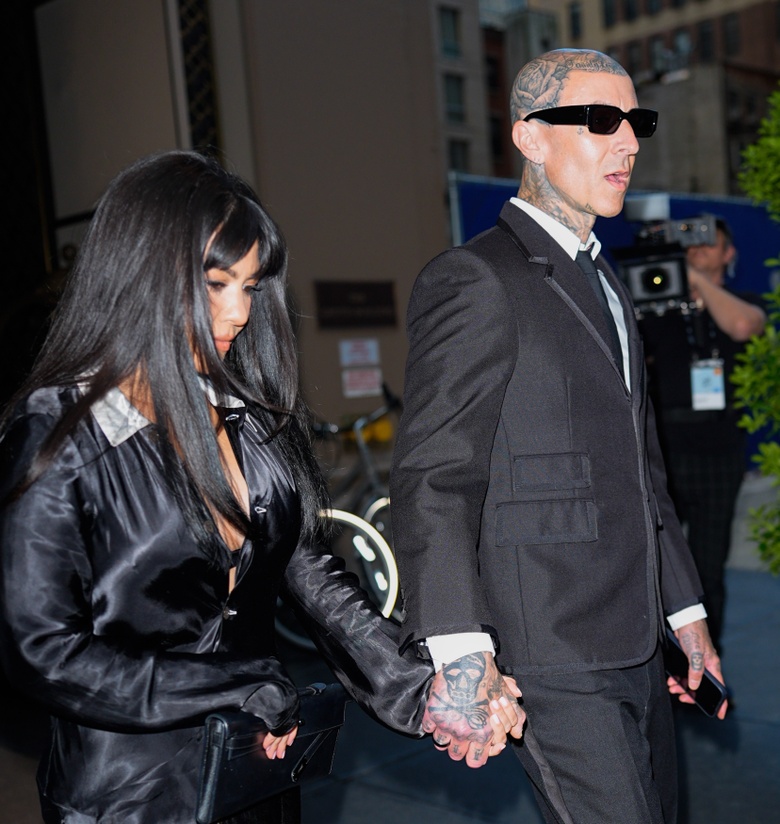 Kourtney Kardashian is posing elegantly at a formal gathering, showcasing a chic ensemble.