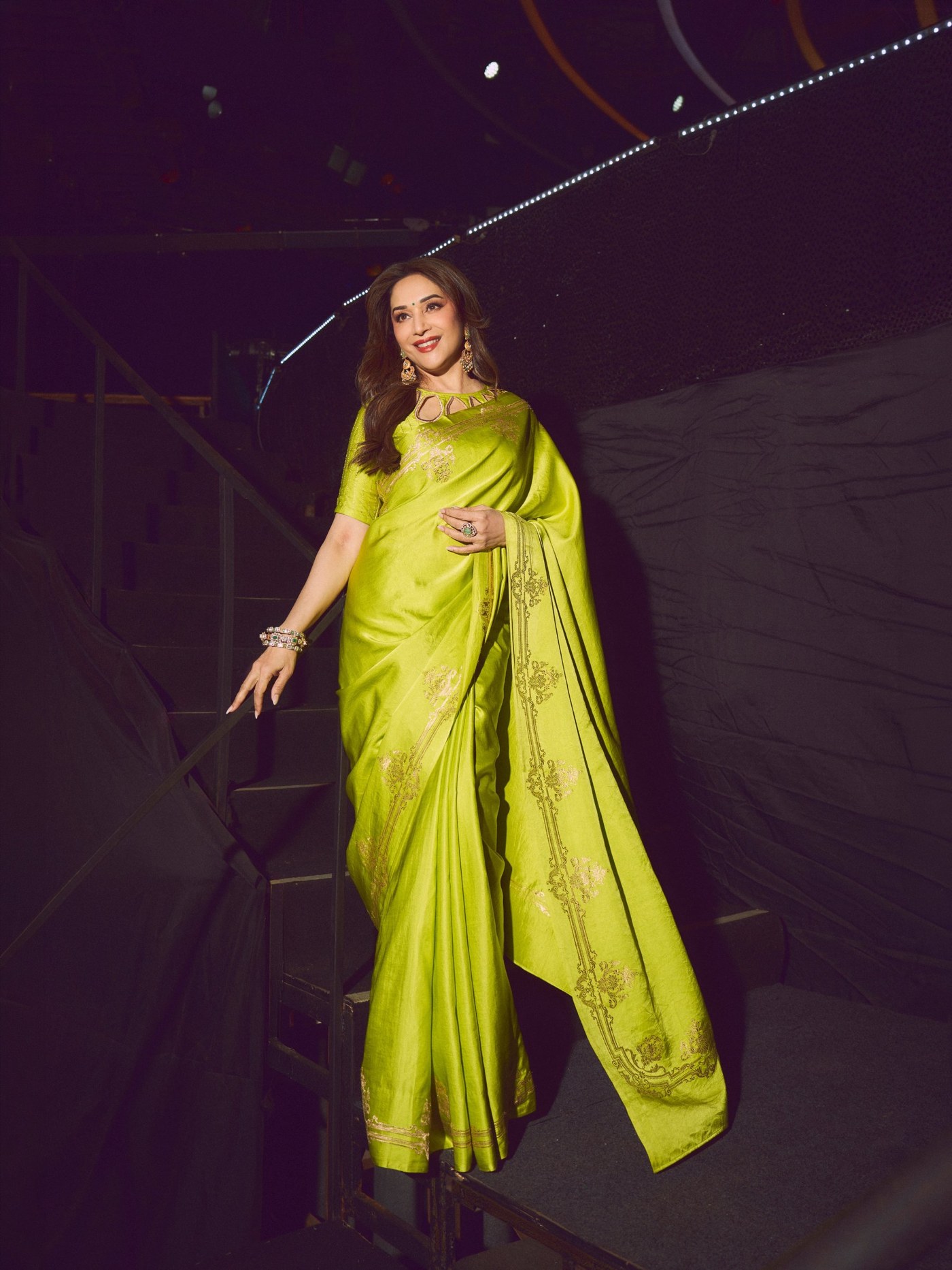 Madhuri Dixit wears a lime green saree against dramatic night lighting. - Photos & Updates