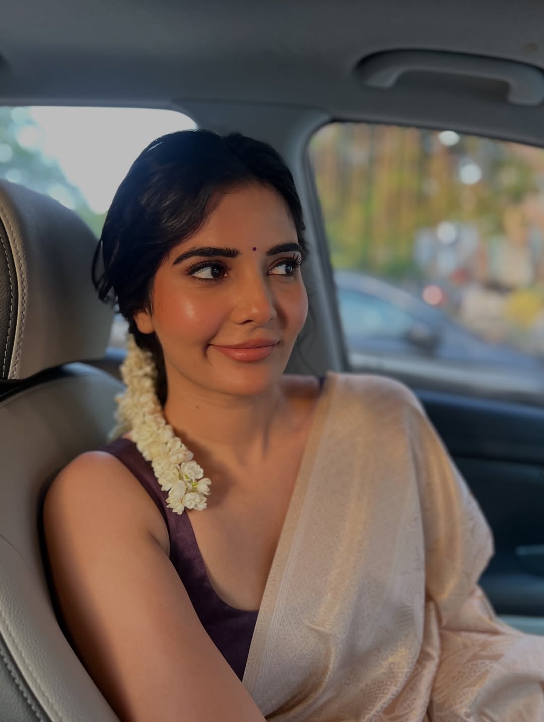 Madhuri Jain resting in a soft pink garment with dark, flowing hair, leaning on a warm surface.