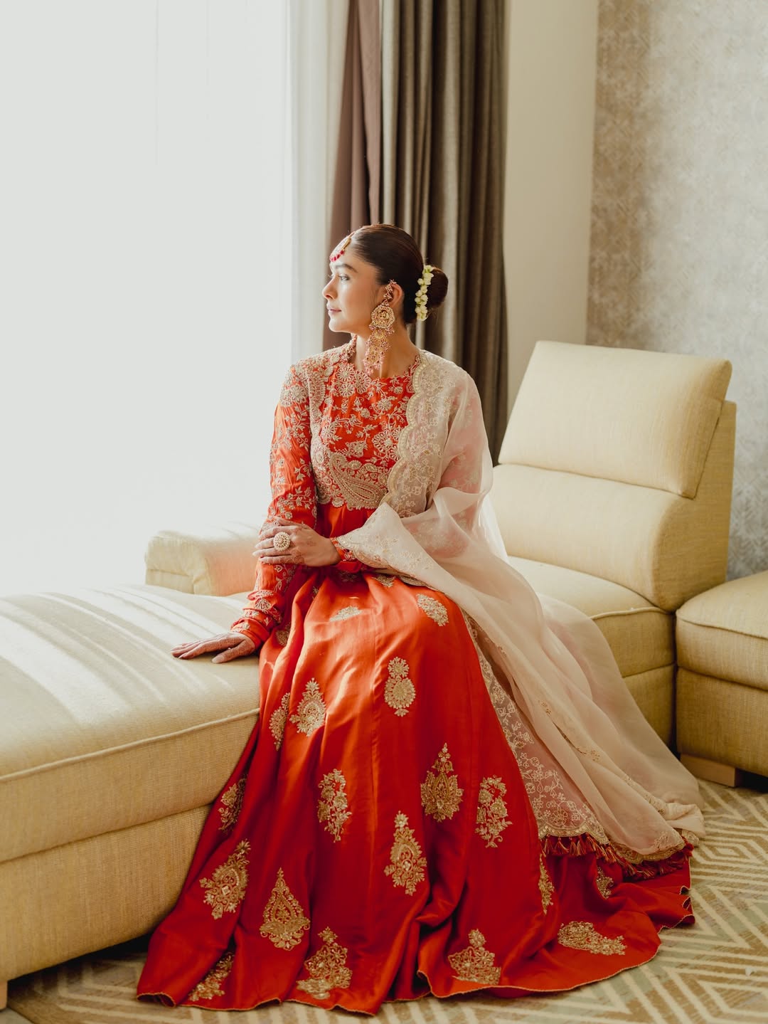 Mrunal Thakur wearing a richly colored, heavily embellished garment with sheer gold fabric draped over her.