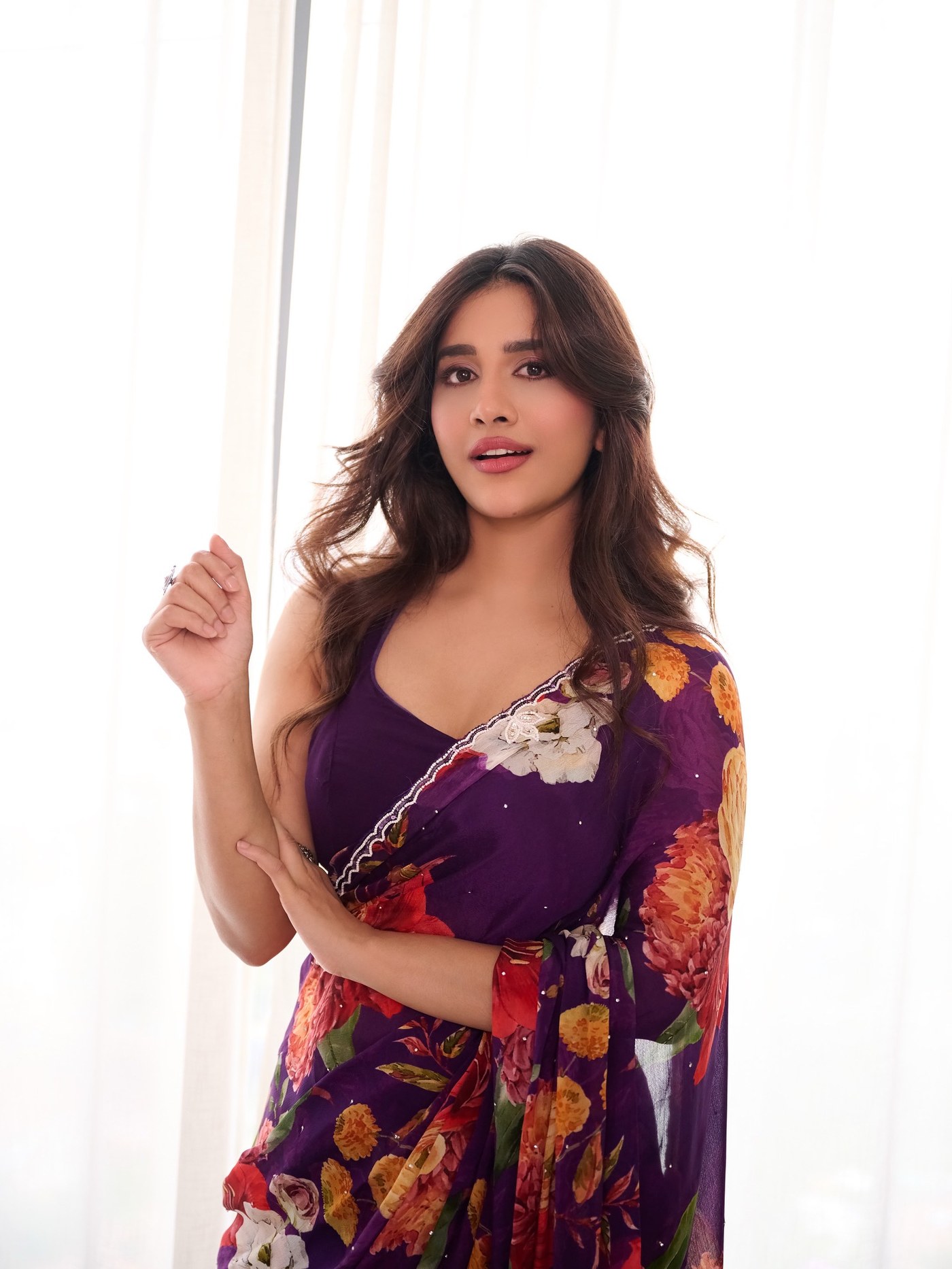 Nabha Natesh is styled in a vibrant floral saree, completing a look that balances traditional textiles with modern styling.