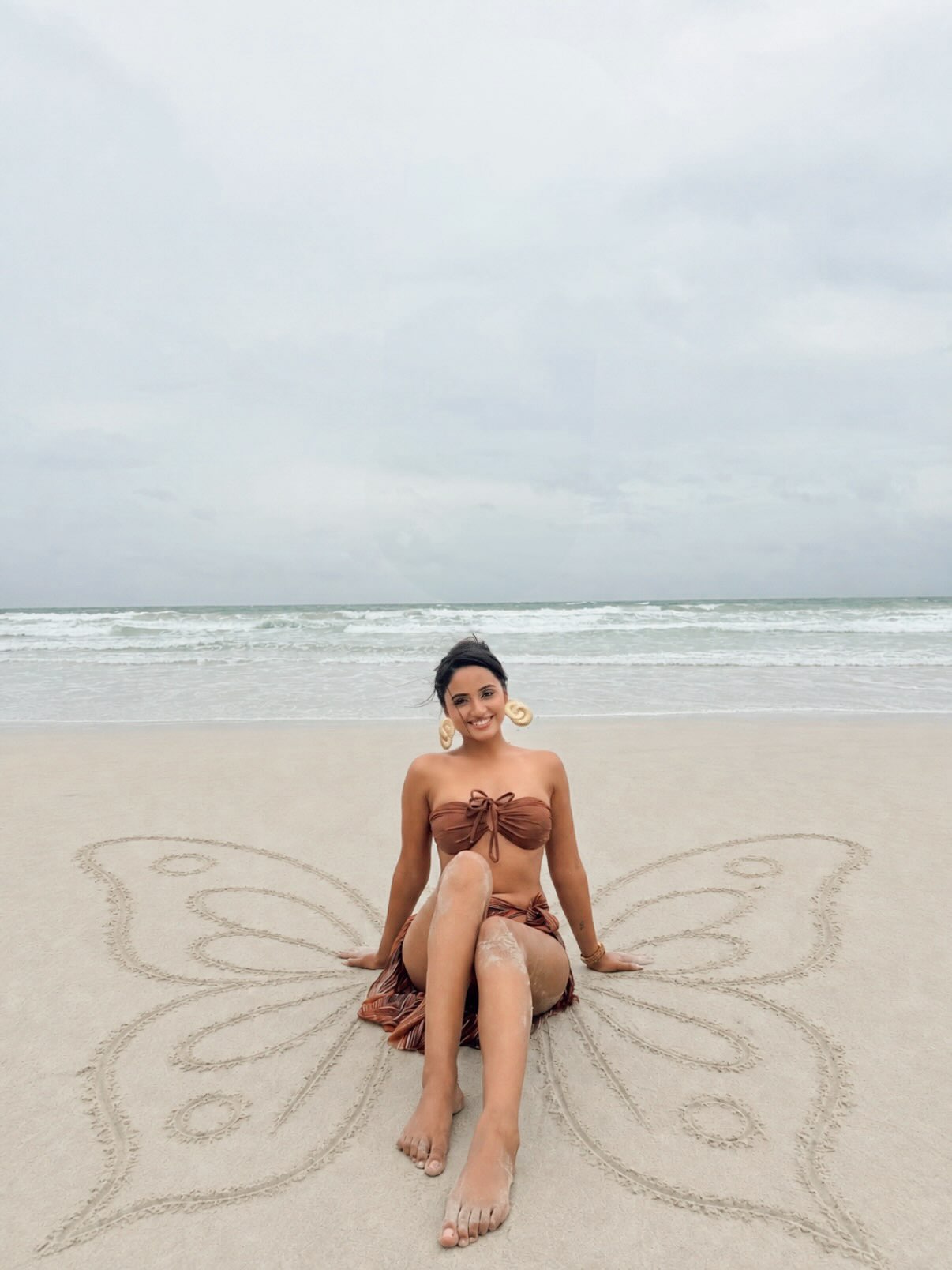 Nisha Guragain models a free-spirited, earthy-toned swimwear look featuring a flowing sarong. - Photos & Updates