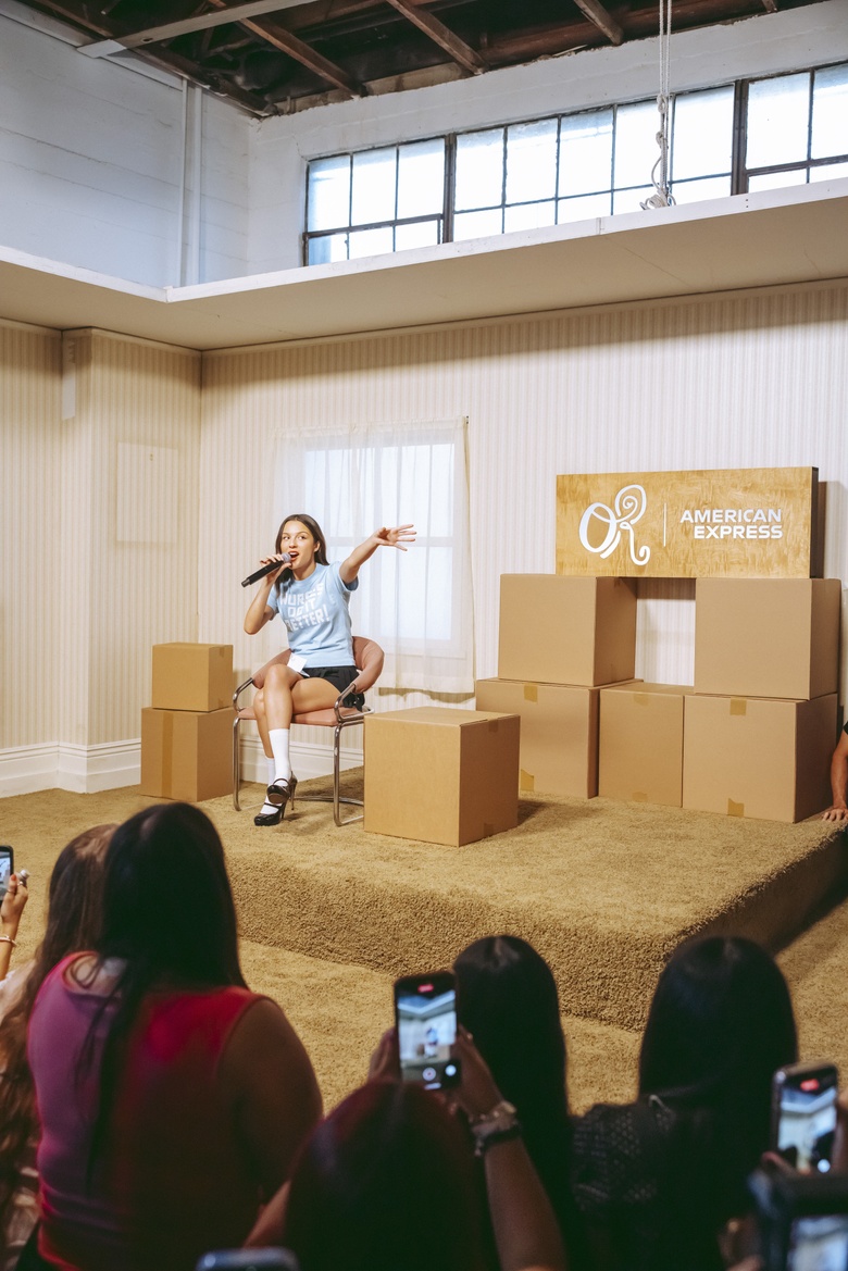 Olivia Rodrigo poses elegantly at an American Express album launch pop-up event.