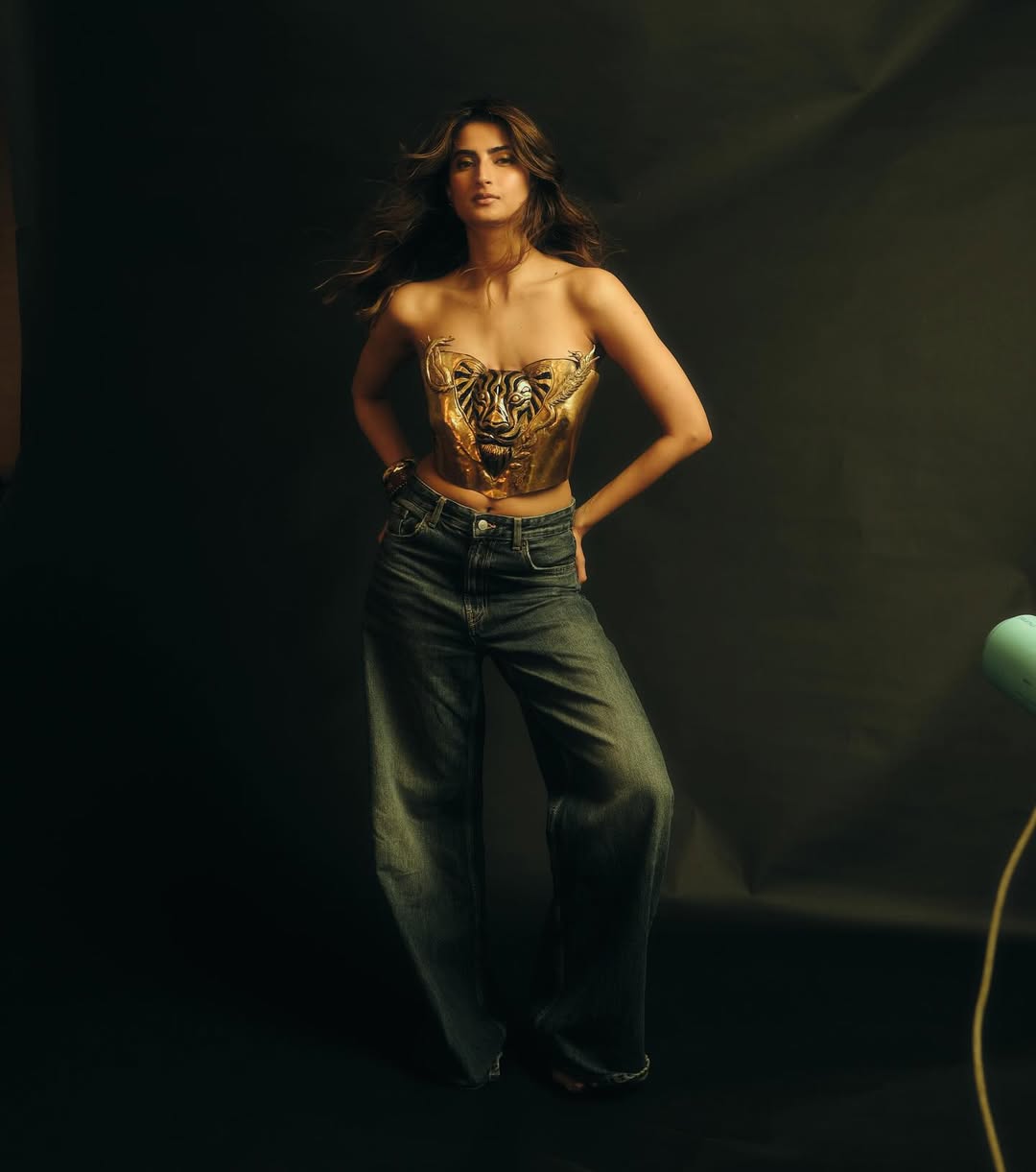 Palak Tiwari in a close-up portrait wearing a golden, textured tiger print garment and gold jewelry.