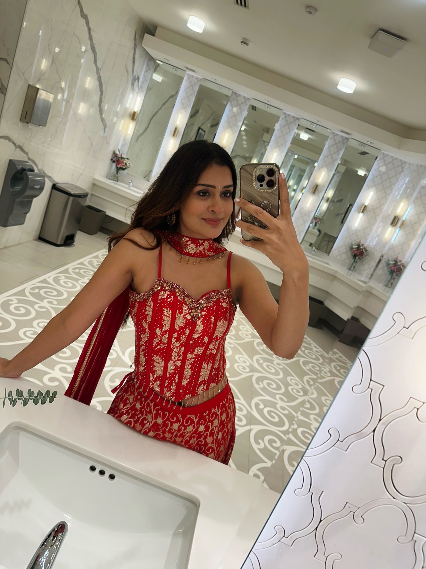 Payal Rajput in a bright red embroidered outfit in a marble restroom. - Photos & Updates