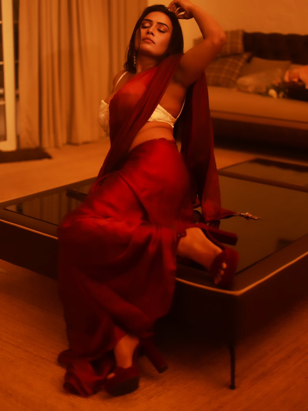 Pihu Singh is leaning forward, resting her right arm on a dark surface, with a large, warm-toned screen behind her.
