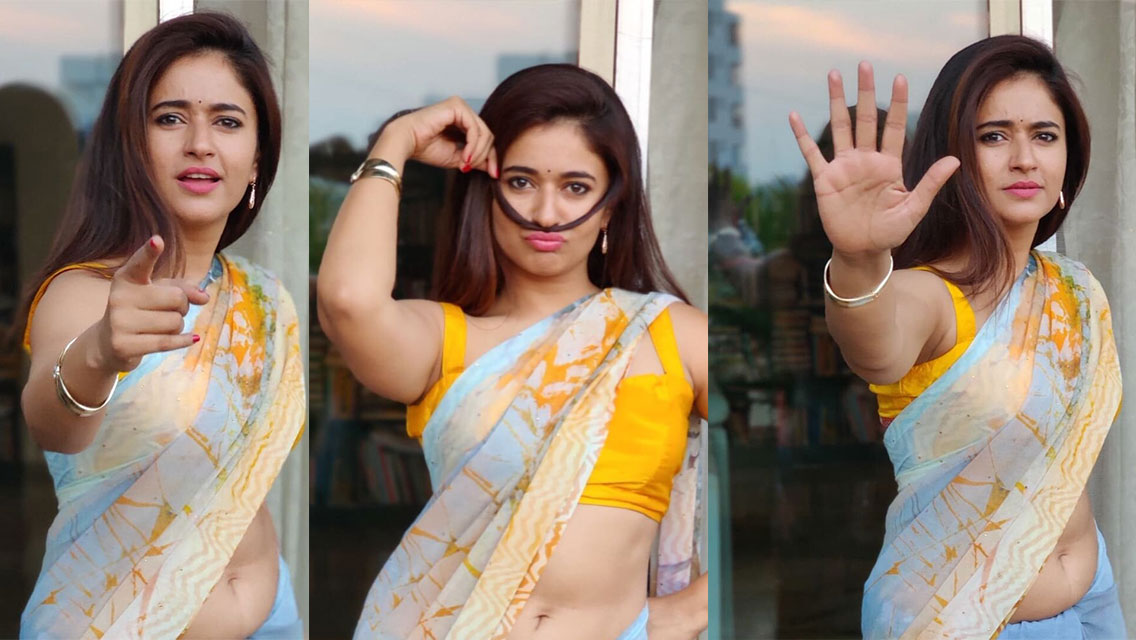 Poonam Bajwa posing indoors, draped in a light blue, abstractly patterned garment with flowing fabric and soft lighting.