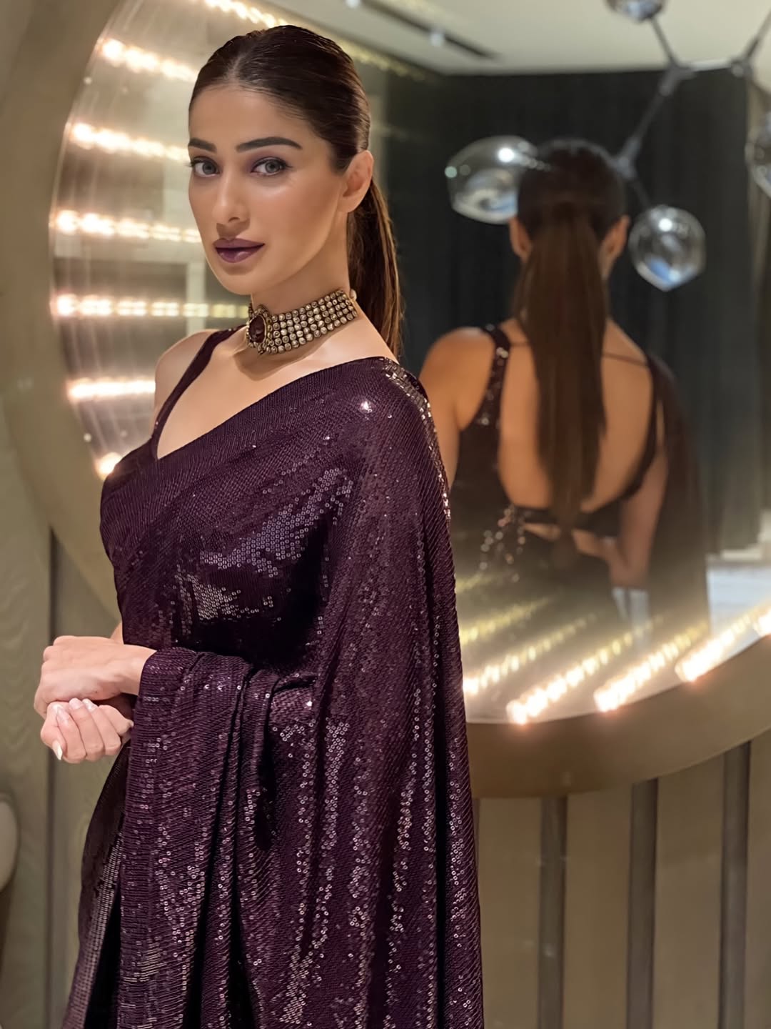 Raai Laxmi poses beautifully in a vibrant red ensemble against an elaborate backdrop.