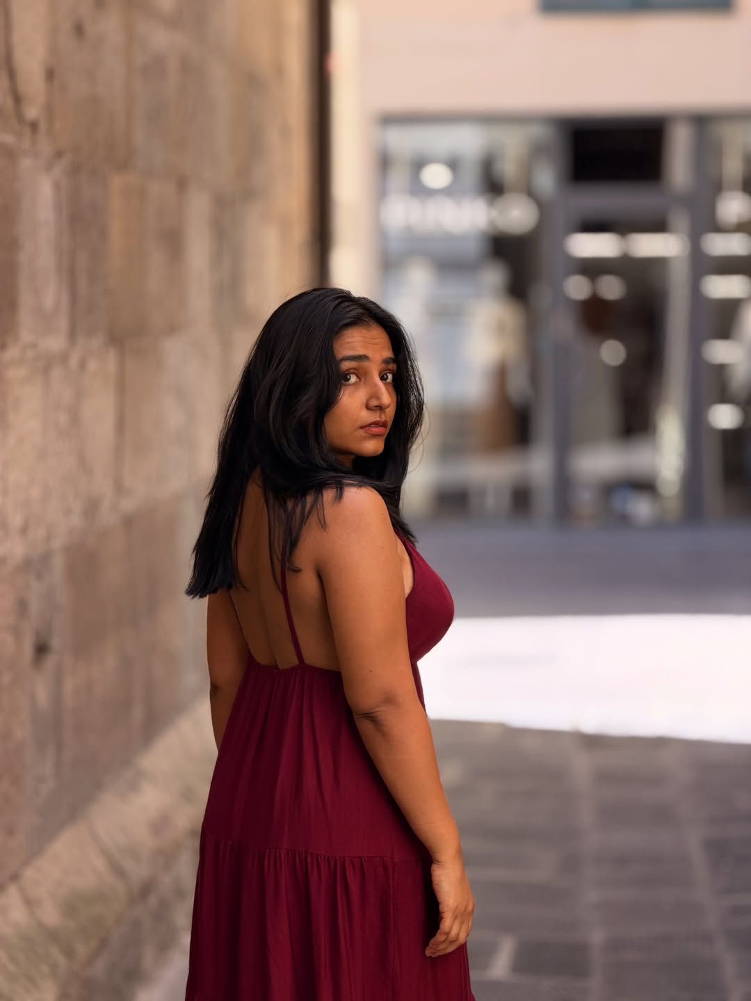 Rajisha Vijayan poses contemplatively in a historic, narrow European alleyway.