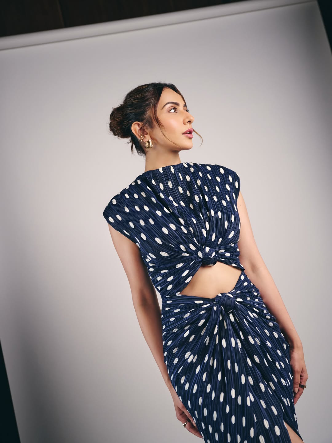 Rakul Preet Singh in a two-piece ensemble against a mottled light blue studio background.