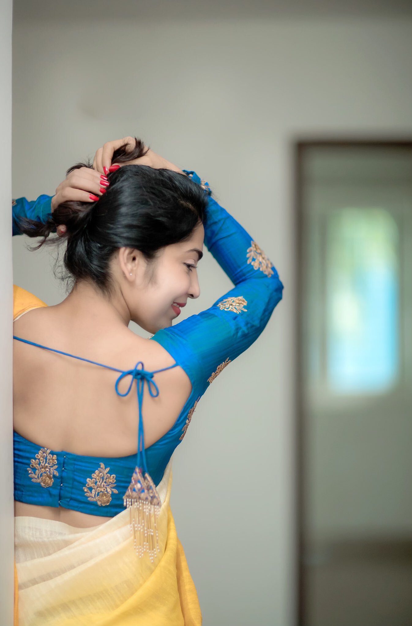 Ramya Subramanian posing outdoors in a teal kurta with red bangles and green foliage.