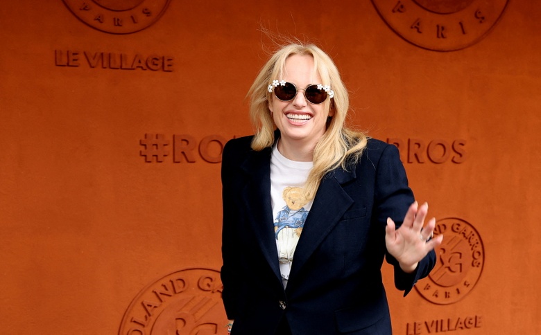 Rebel Wilson posing confidently in a vibrant, colorful setting with striking fashion choices.