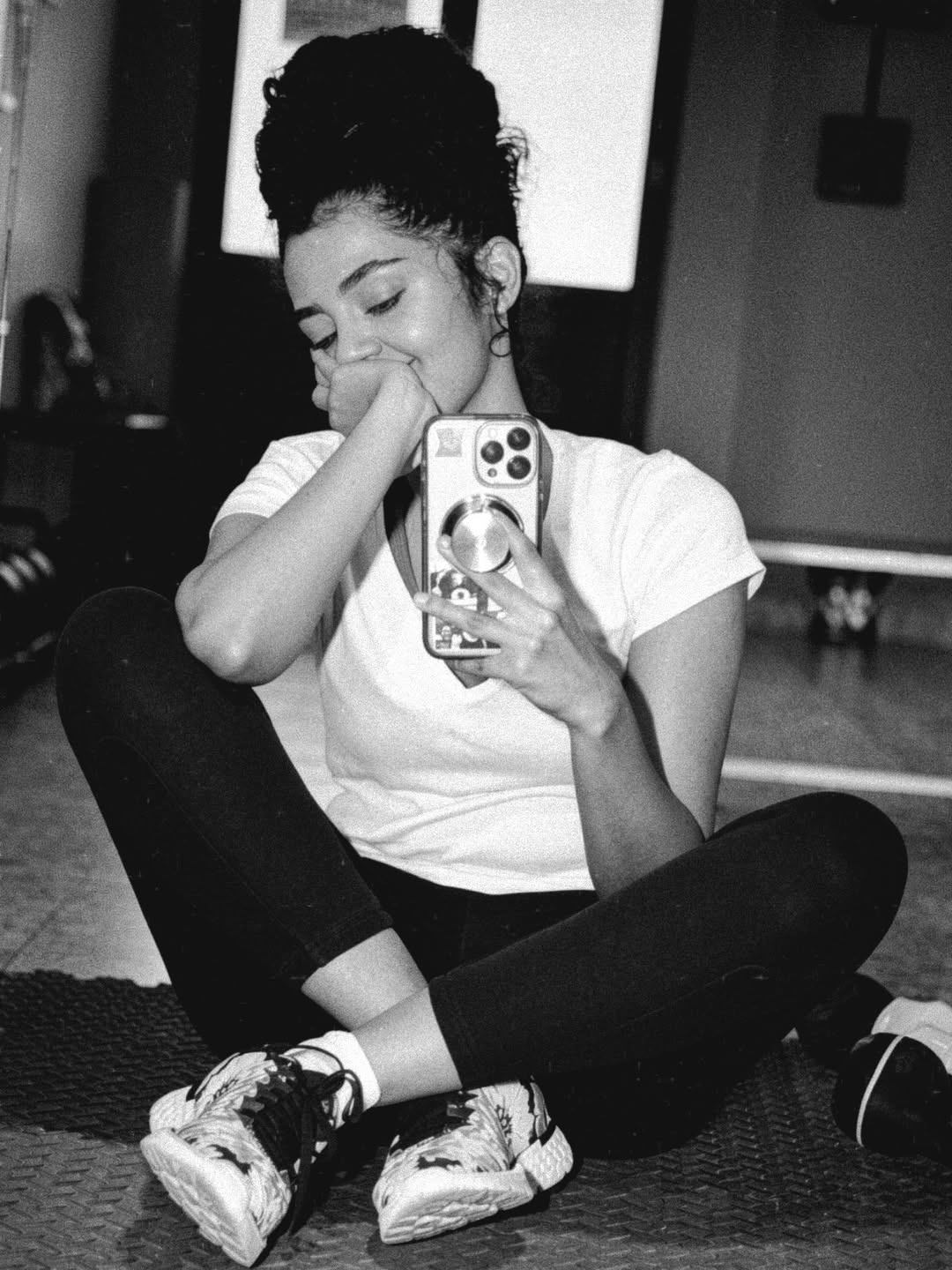 Anupama Parameswaran taking a mirror selfie leaning against a glossy surface.