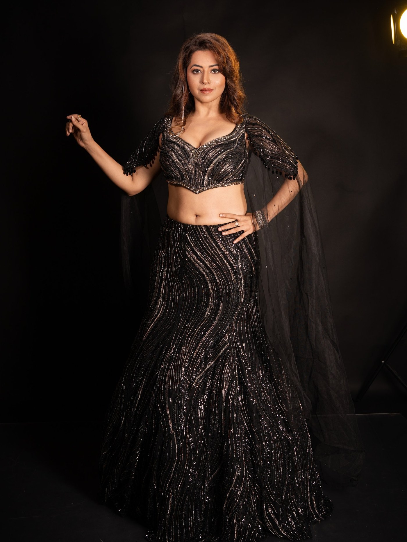 Ridheema Tiwari in a black, shimmering ensemble under low-lit studio conditions. - Photos & Updates