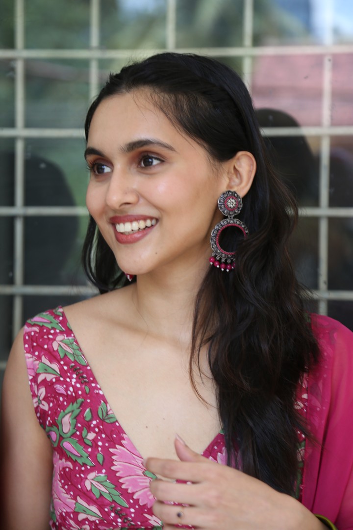 Riya Jithu poses beautifully outdoors wearing a vibrant yellow and red ensemble with intricate detailing.