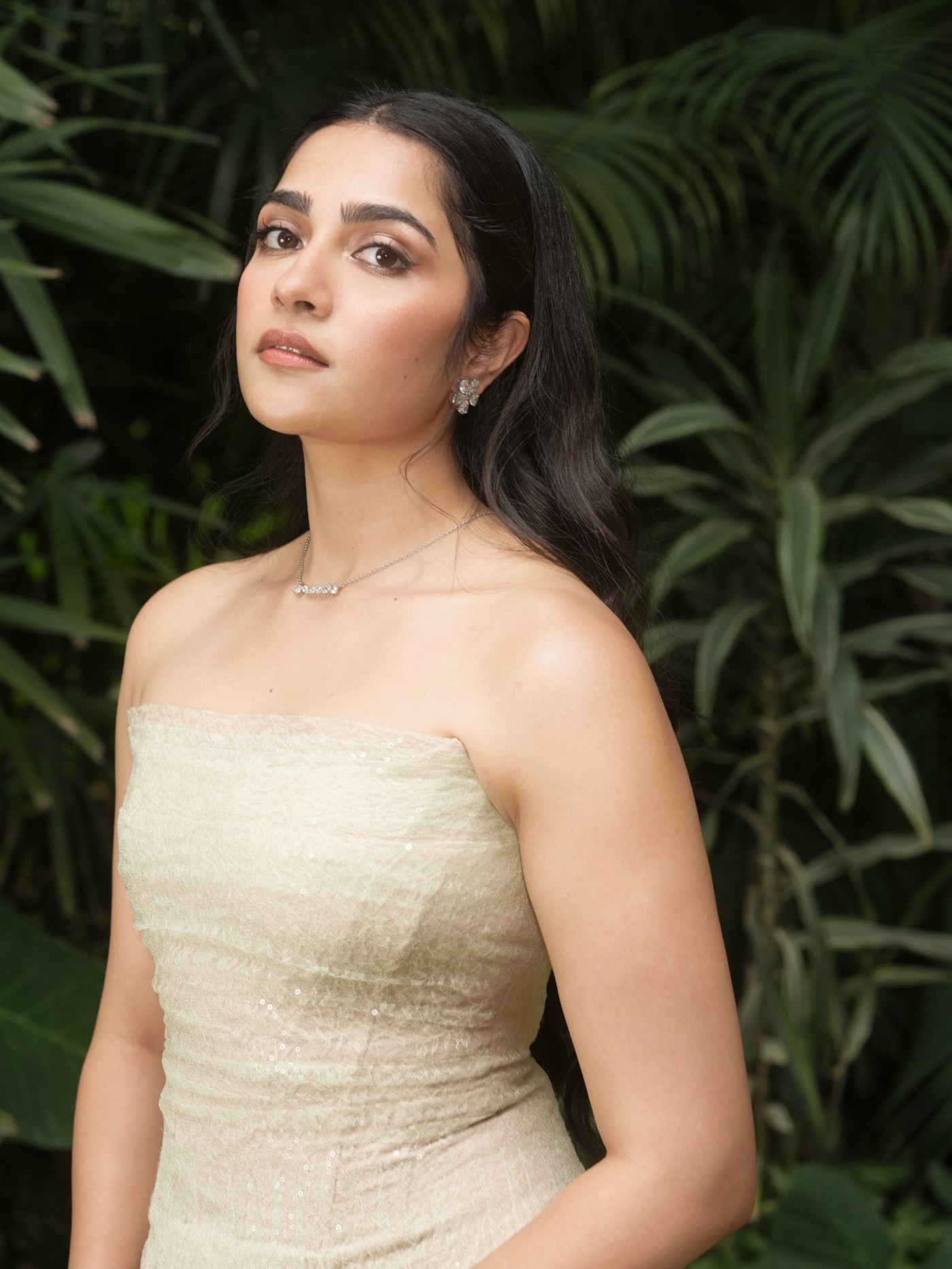 Rukmini Vasanth poses in a cream-toned ensemble, embodying sophisticated quiet luxury against lush greenery. - Photos & Updates