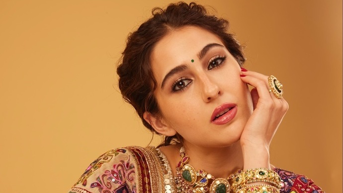 Sara Ali Khan poses elegantly in a vibrant outfit at an event.