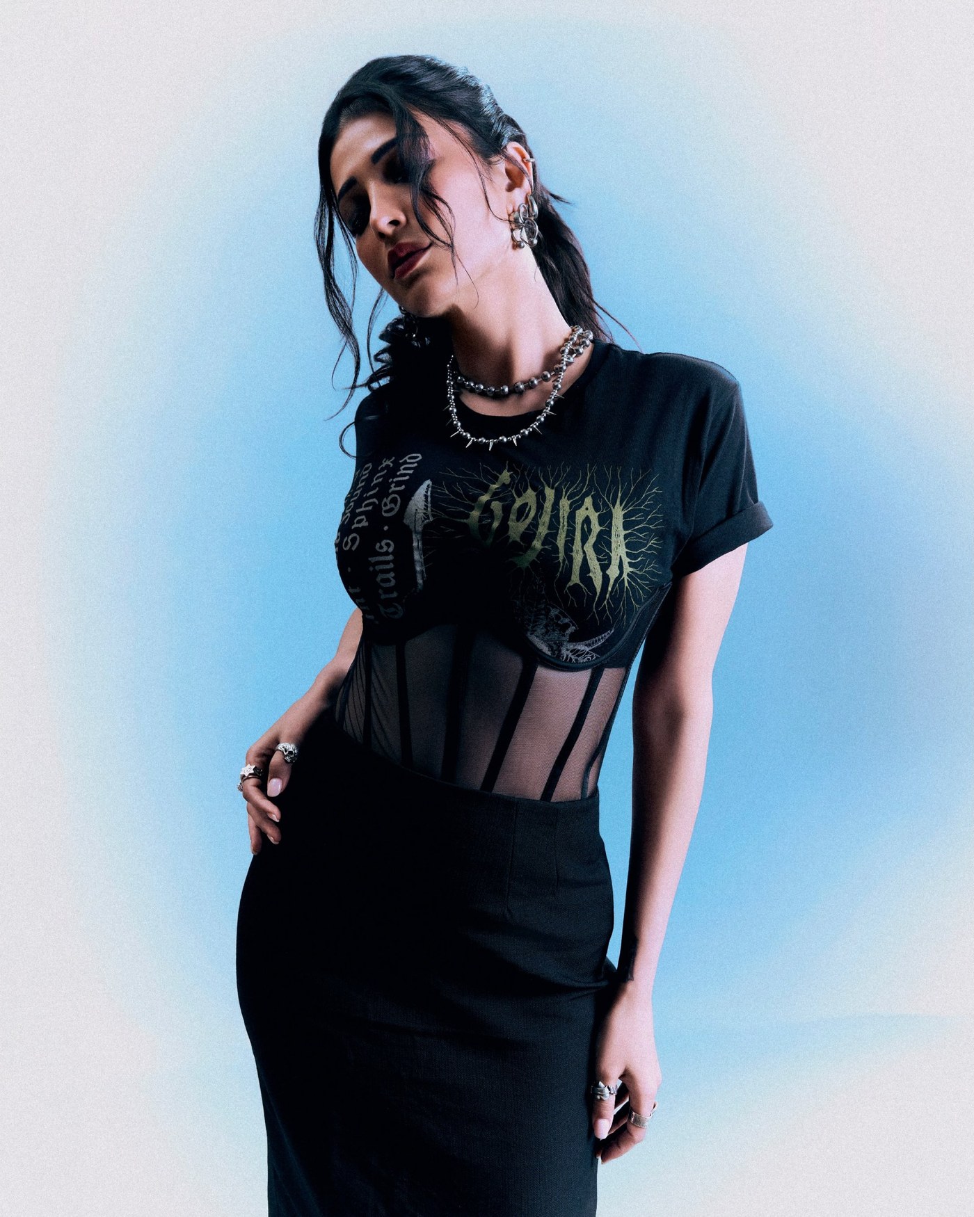 Shruti Haasan in a black, rock-chic ensemble against a vibrant blue backdrop. - Photos & Updates