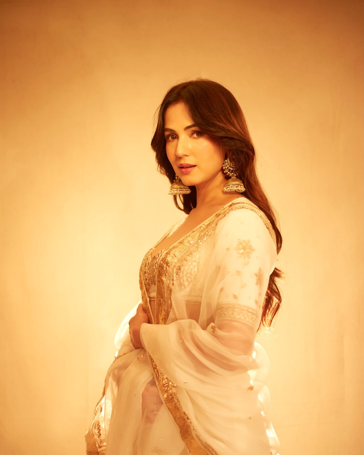 Sonal Chauhan is captured wearing a stunning cream-and-gold embroidered traditional saree at a celebratory event.