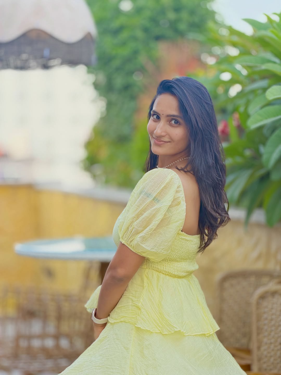 Sravya Chowdary models a ruffled, pastel yellow tiered dress outdoors. - Photos & Updates