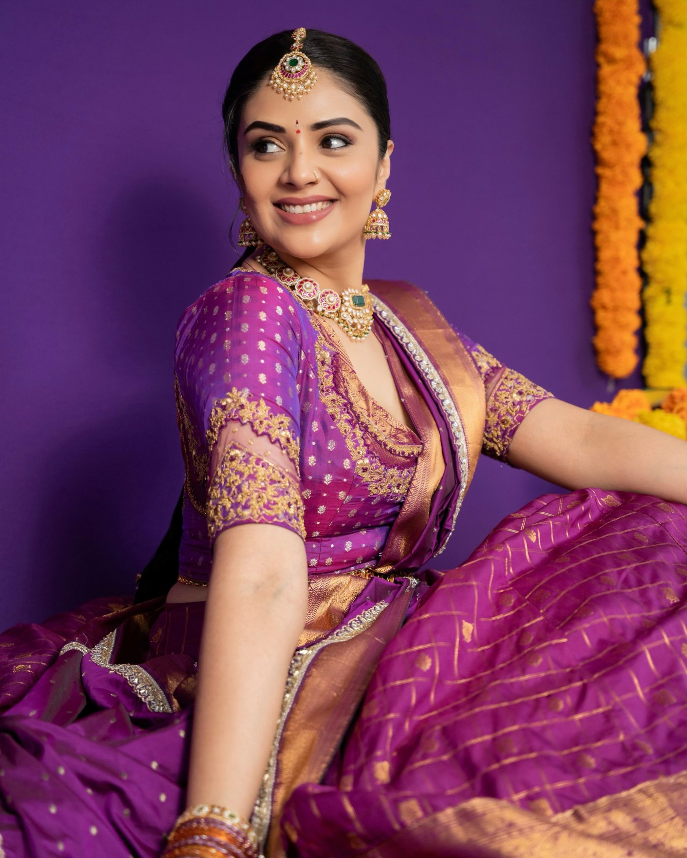 Sreemukhi models a stunning purple silk saree, adorned with gold jewelry and fresh jasmine accents in her braid. - Photos & Updates