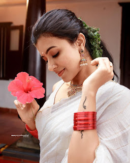 Anju Kurian standing and holding a plate of yellow and orange flowers, presenting them toward the viewer.
