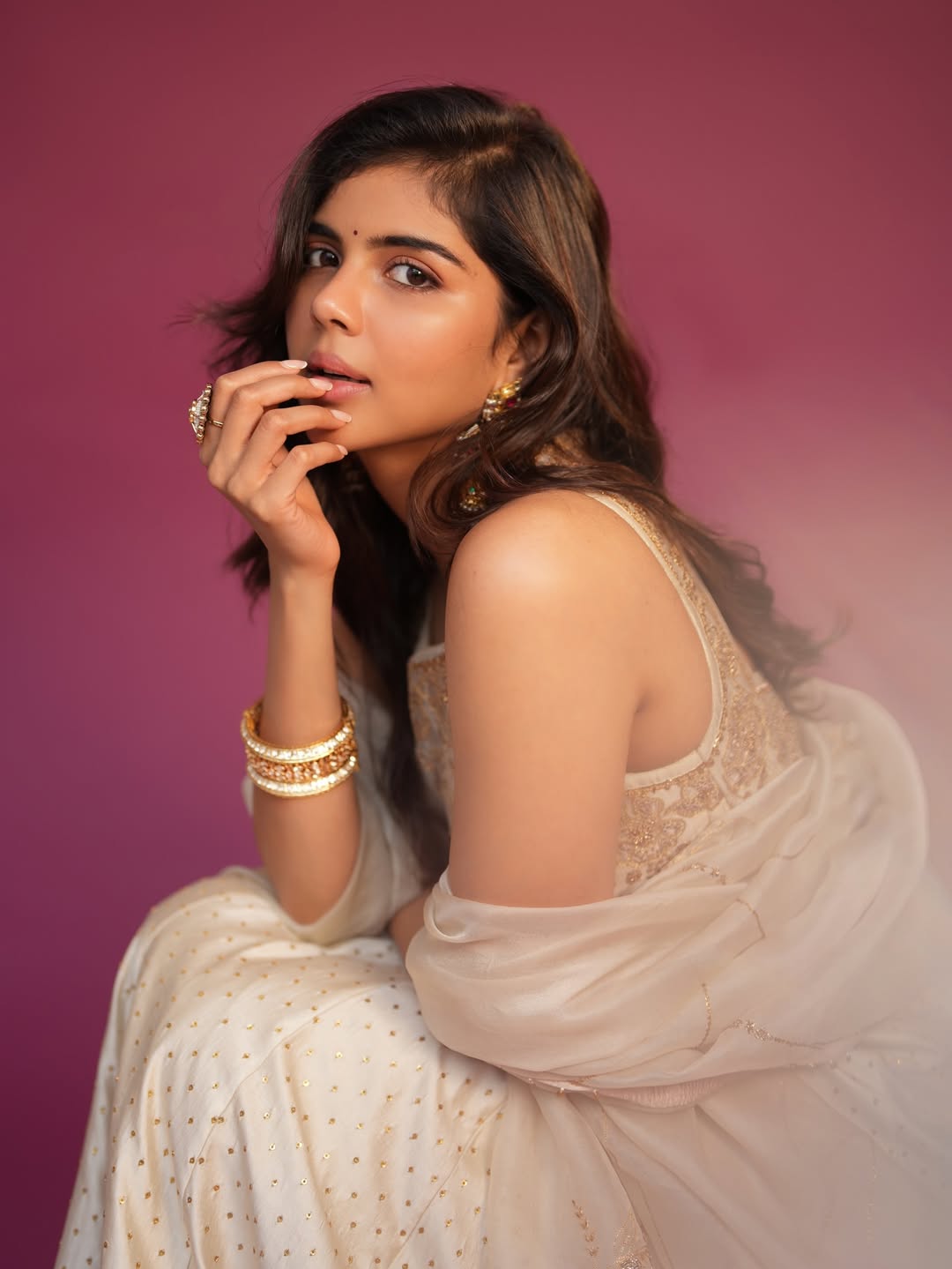 Kalyani Priyadarshan posing on a wooden pier overlooking the blue sea with a shimmering dress.