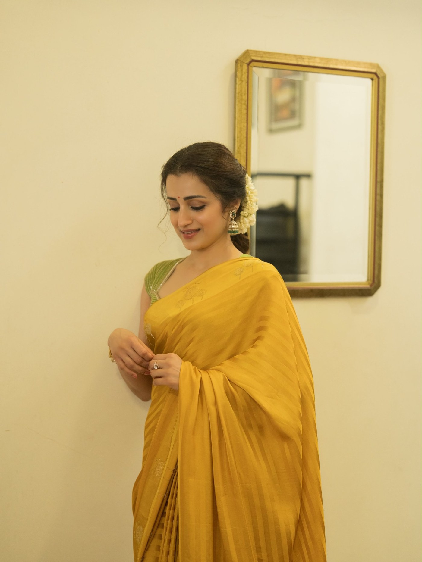Trisha Krishnan is seen radiating elegance in a yellow saree paired with a green blouse.
