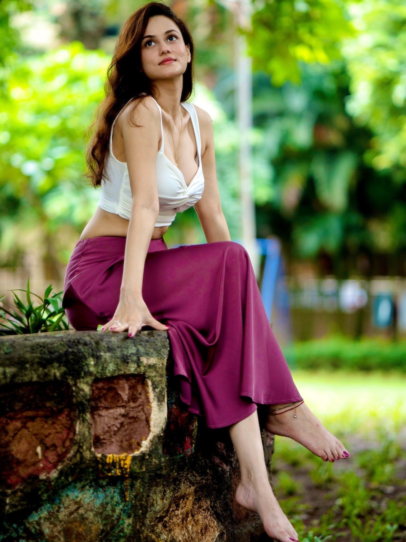 Urvashi Pardeshi wears a white cropped top and a flowing magenta skirt in a garden setting. - Photos & Updates